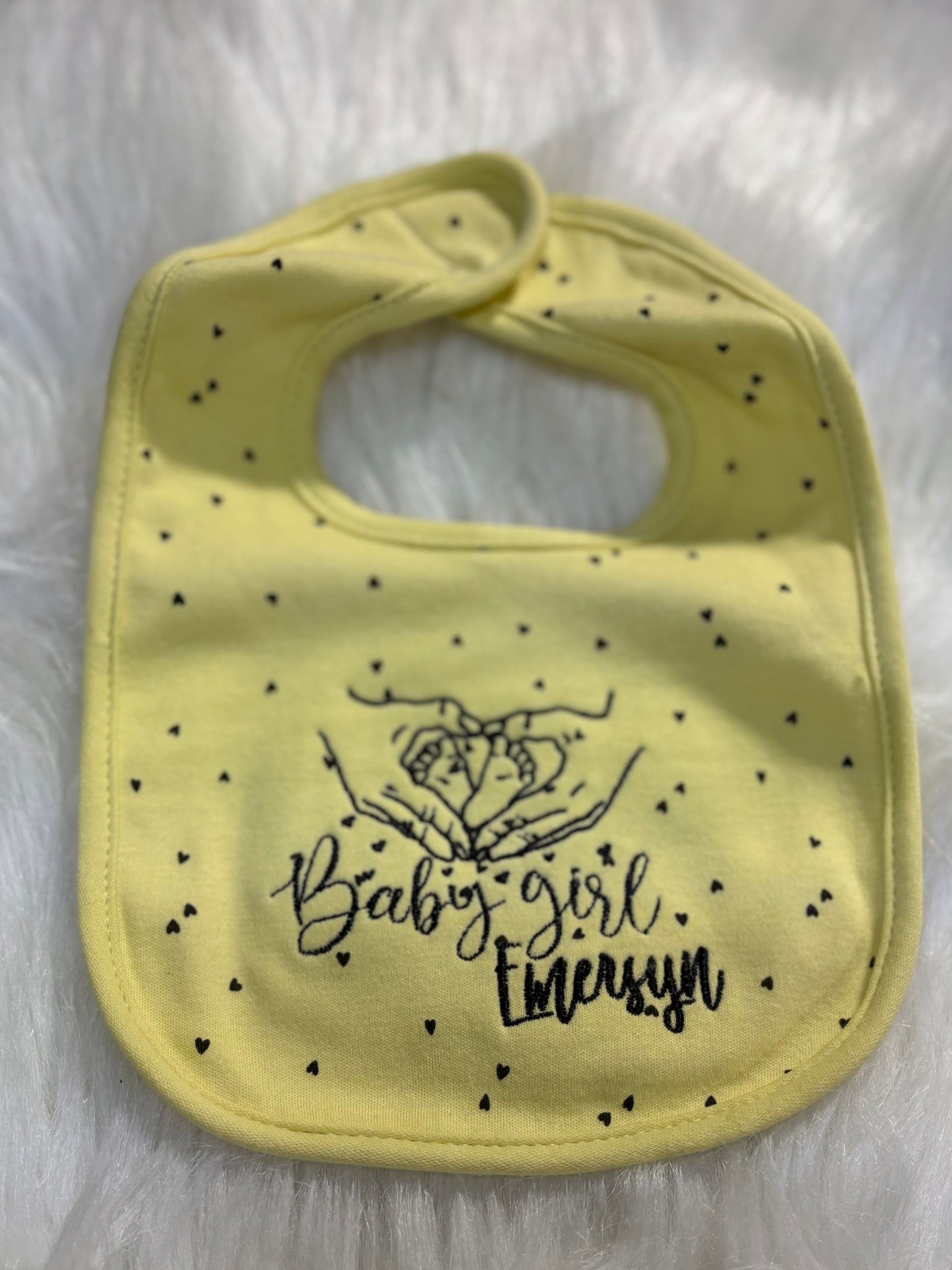 Yellow bib with black text and polka dots on a white fur background
